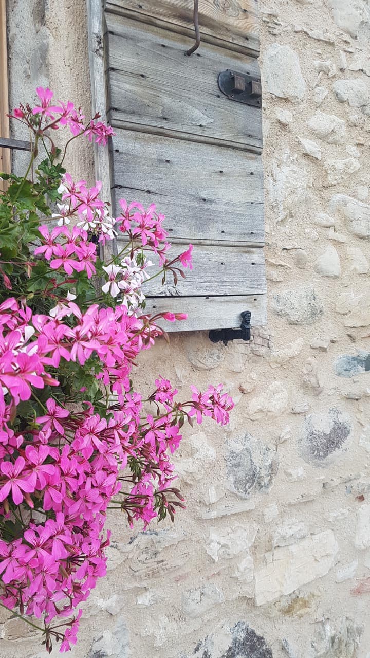 Persiana in legno antico con bandella su muro in pietra delle Dolomiti